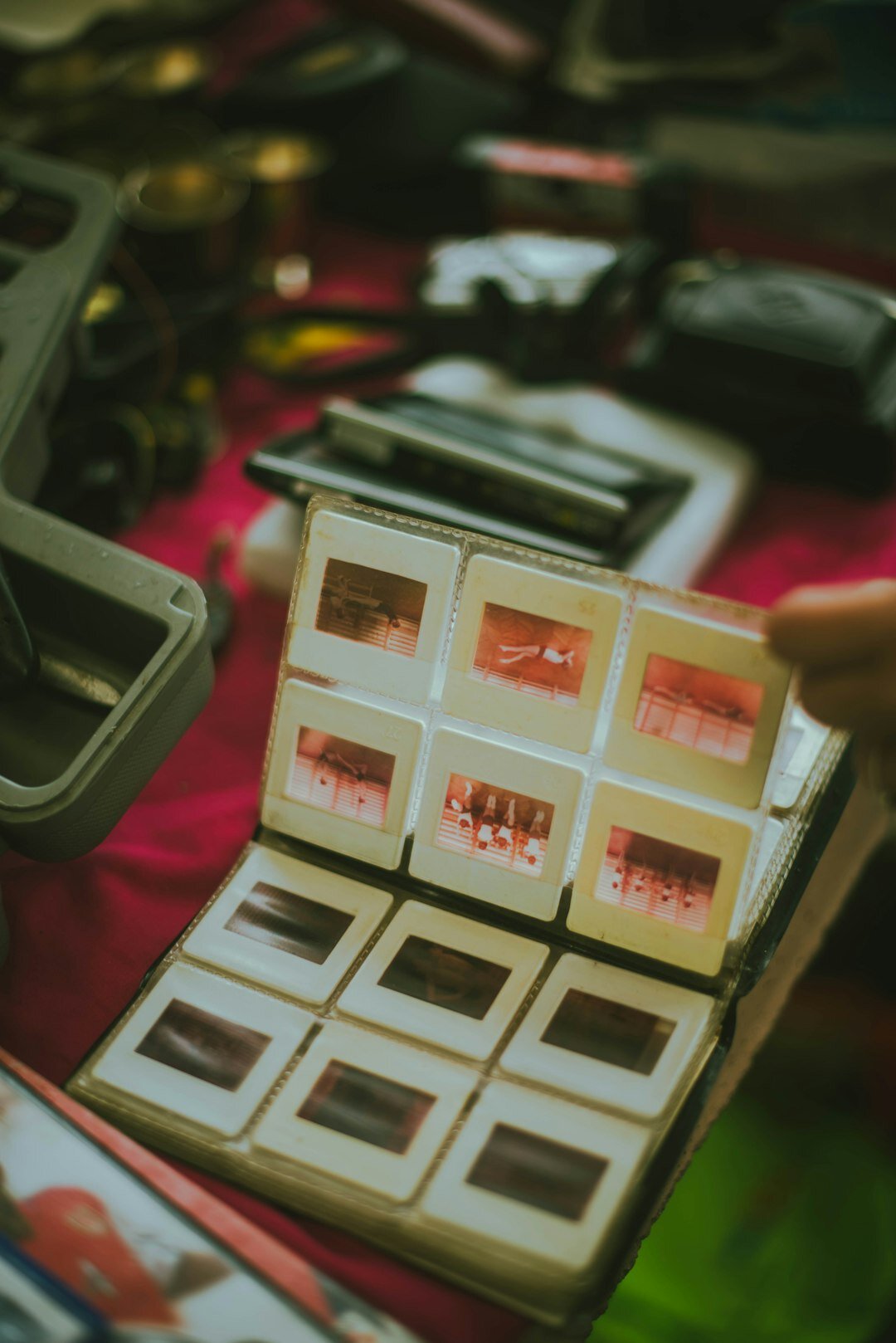 Hands reviewing printed photo contact sheets with a loupe
